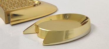 Two shiny gold metallic objects with curved shapes on a white surface.