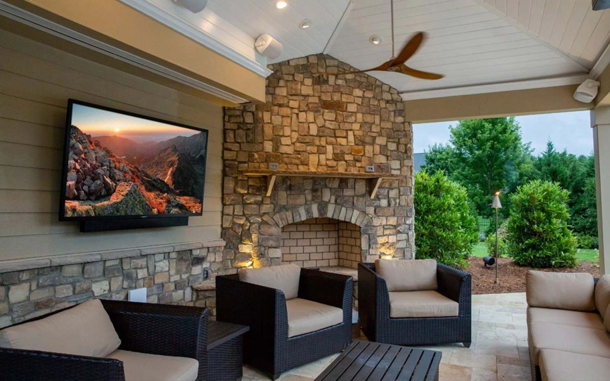 Cozy outdoor patio with stone fireplace and mounted TV.