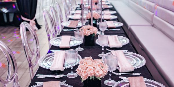Elegant table setting with pink roses and transparent chairs for a formal event.