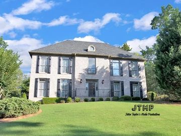 Large two-story house with manicured lawn and shrubs.