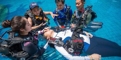 Five scuba students practicing rescue scenarios in pool