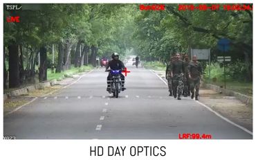 Security camera view of a motorcyclist and soldiers on a tree-lined street.