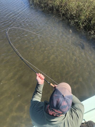 An angler connected to a redfish on a fly rod in the clear winter waters of Northeast Florida
