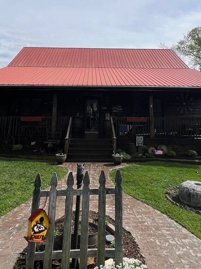 Rustic house with a red roof and a picket fence.