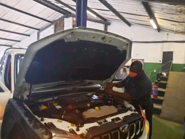Mechanic working on a car engine in a garage.