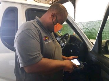 Man wearing a mask using a device inside a car.