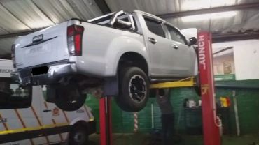 White pickup truck lifted on car lift in garage.