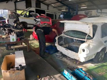 Mechanic working on disassembled white car in workshop.