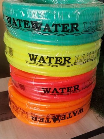 Stack of colorful water pipes wrapped in plastic on a wooden table.
