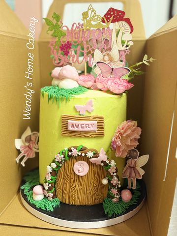 Whimsical fairy-themed birthday cake with door and floral decorations.