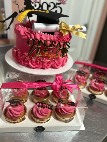 Pink graduation-themed cake and cupcakes with congratulatory decorations.