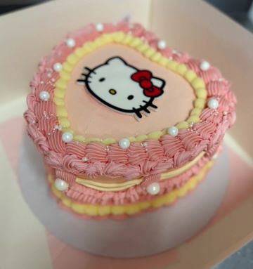 Heart-shaped cake decorated with Hello Kitty and pink frosting pearls.
