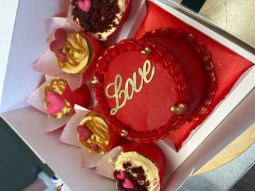 Red-themed cake and cupcakes with love decorations in a box.