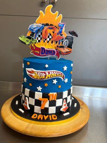 Two-tier Hot Wheels-themed birthday cake with flames and race cars.