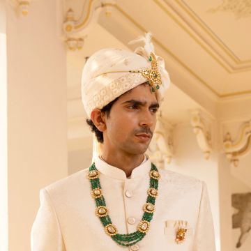 Man dressed in traditional Indian wedding attire with turban and jewelry.