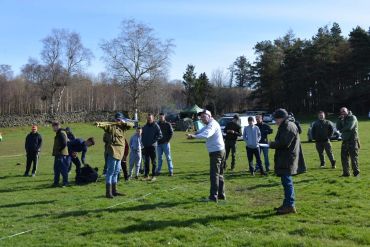 Group outdoors with one aiming a slingshot.