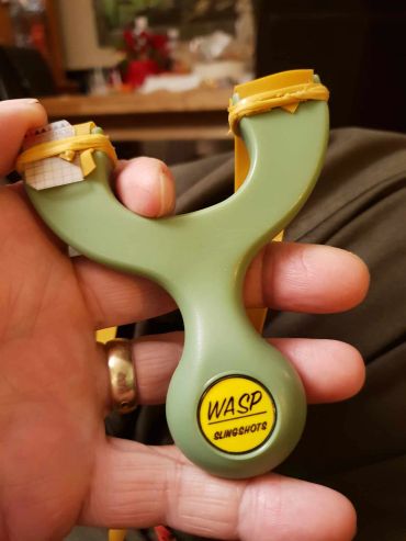 Hand holding a WASP slingshot with rubber bands.