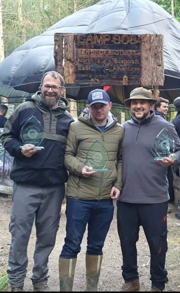 Three men holding awards at Camp Bob outdoor event.