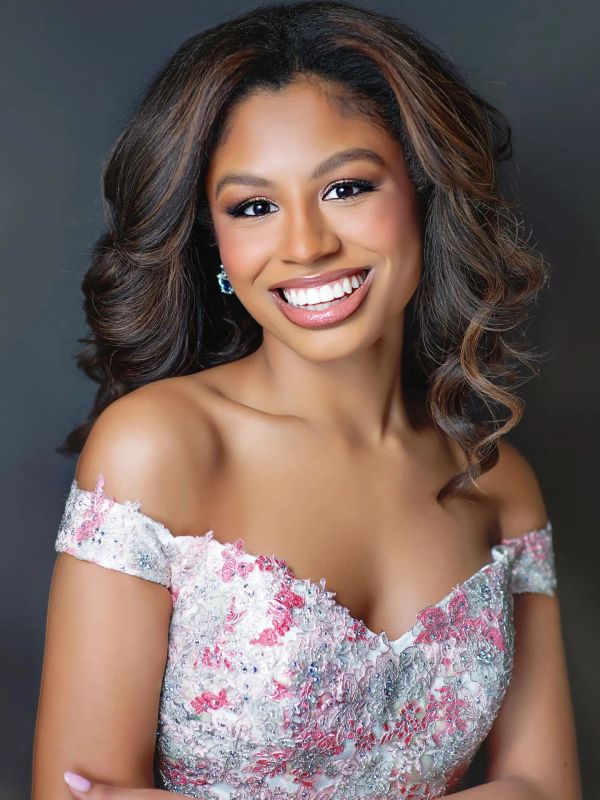 Woman smiling in a floral off-shoulder dress.