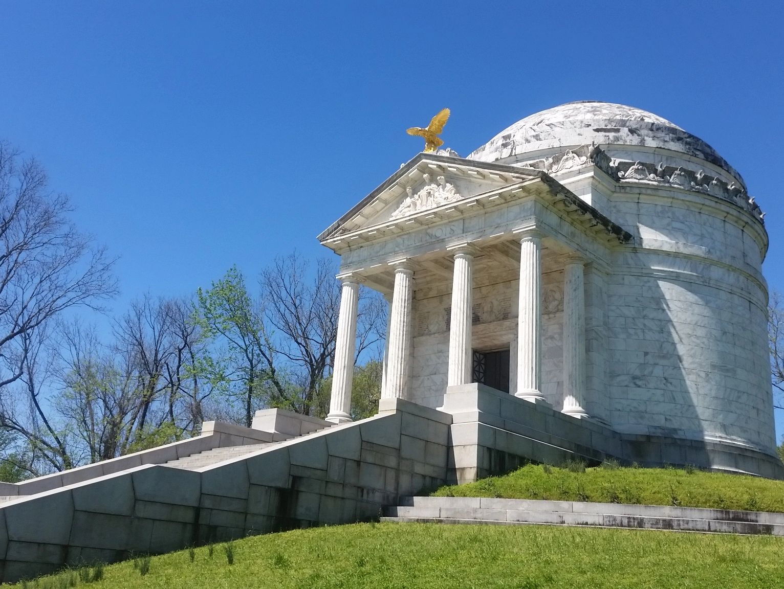 Historic white marble monument with columns and a golden eagle on top.