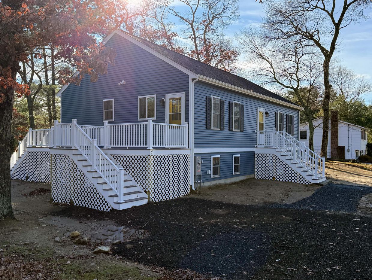 Blue house with white railings and lattice under raised porch.
