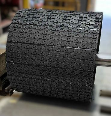 Large industrial conveyor drum with textured black pulley lagging