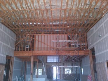 Interior of a building under construction with exposed wooden framing and scaffolding.