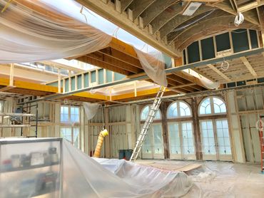 Interior of a house under construction with exposed framing and plastic coverings.
