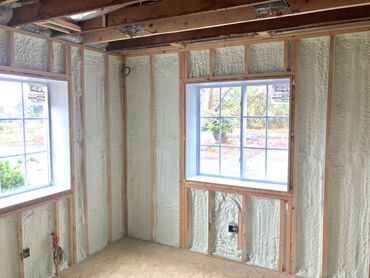 Room with spray foam insulation and two windows.