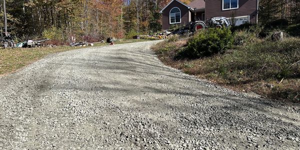 Gravel driveway leading up to a house surrounded by autumn trees.