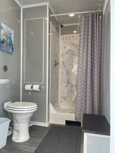 Interior of 3 stall restroom with shower and toilet.