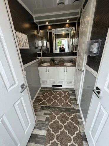 Interior of 6 stall restroom trailer with two sinks and 3 stall doors. Mirror and LED lights.