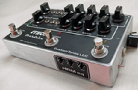 Close-up of an analog delay guitar effects pedal with knobs and footswitches.