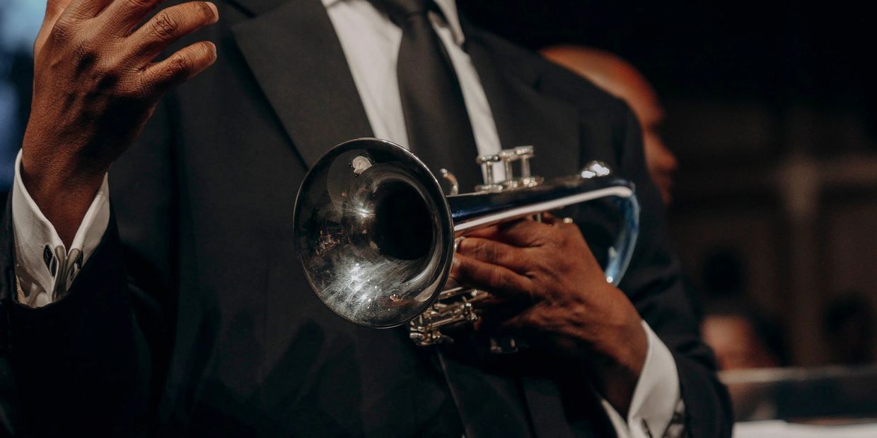 A musician in a suit holding a trumpet, ready to play.