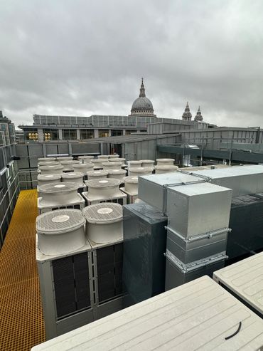 Rooftop HVAC units with St. Paul's Cathedral in the background under cloudy skies.