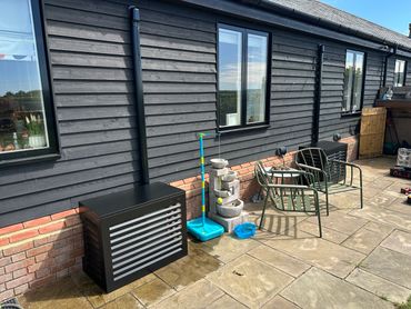 Outdoor patio with metal chairs, a water fountain, and a dark wooden house exterior.