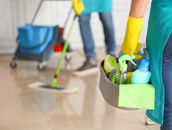 Janitor woman with cleaning supplies in kitchen