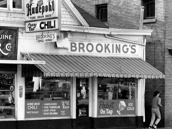 Black-and-white photo of Brookings chili restaurant with signage and a person walking by.