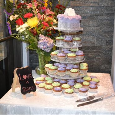 Cupcake tower with pastel frosting and floral arrangement on a decorated table.