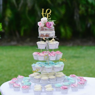 Elegant cupcake tower with a small cake topped by roses and a LOVE sign.