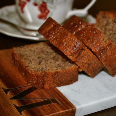 Slices of moist banana bread on a wooden and marble cutting board.
