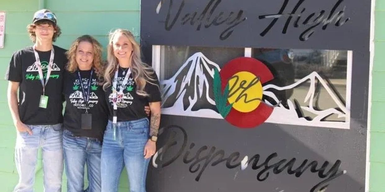 Three people standing in front of Valley High Dispensary sign.