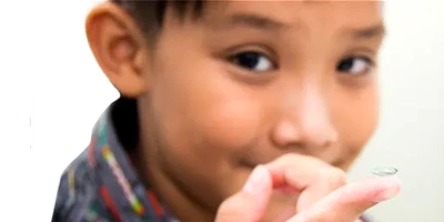 Boy holding a contact lens on his finger.
