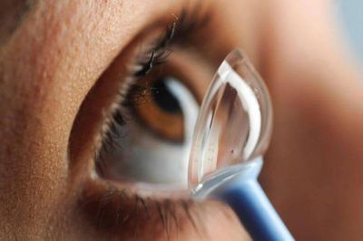 Close-up of applying a contact lens to an eye.