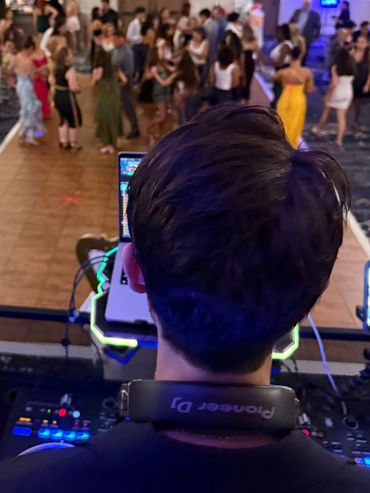 DJ playing music at a lively party with people dancing.