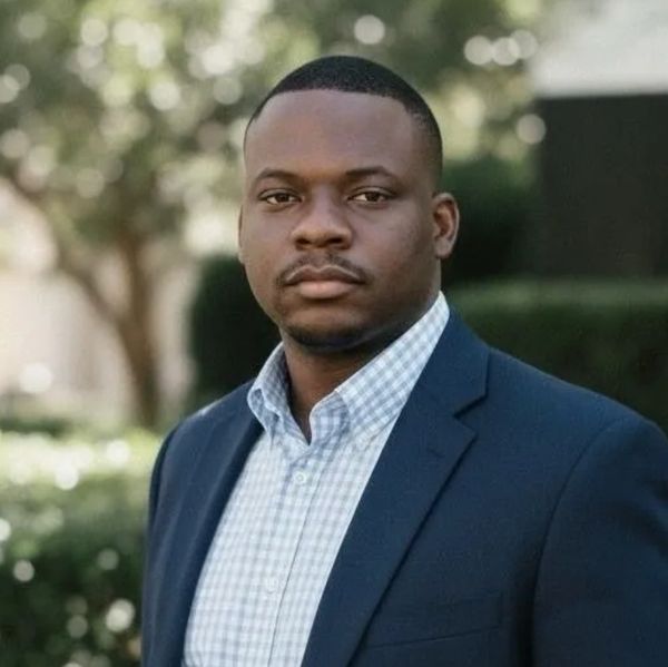Professional man in a blue blazer and checkered shirt outdoors.