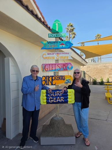 Two people posing by a colorful signpost with beach and bike rental info.