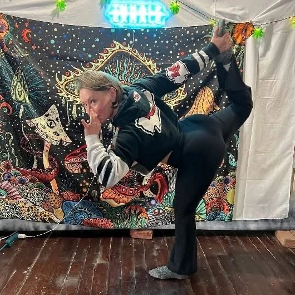 Person striking a yoga pose indoors against a colorful tapestry backdrop.