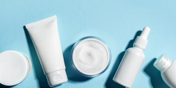 Various white skincare product containers on a blue background.