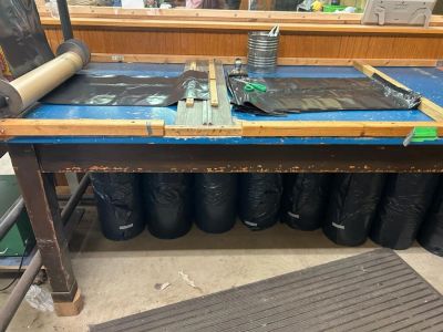 A workbench with black trash bags stored underneath and tools on top.
